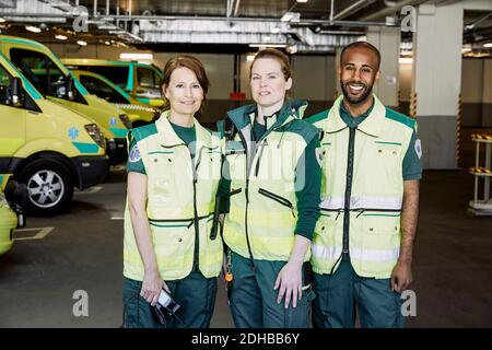 Portrait of confident paramedics standing against ambulance in parking lot Stock Photo