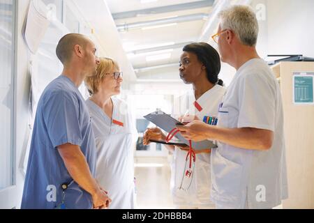 Male and female doctors discussing over digital tablet while standing in corridor at hospital Stock Photo