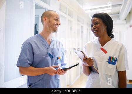 Happy medical professionals in uniform discussing at hospital corridor Stock Photo