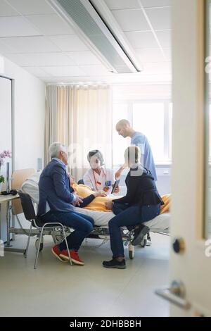 Healthcare workers discussing with patient and her friends in hospital ward Stock Photo