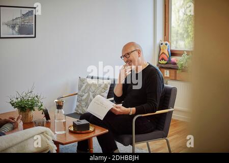 Confident smiling doctor with reports talking to patient during therapy session Stock Photo