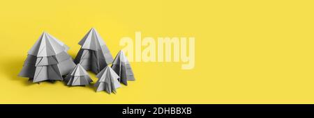 Simple origamy 3D Christmas tree made from gray paper on yellow backround. Yellow and Gray Colors new colors of 2021 year Stock Photo