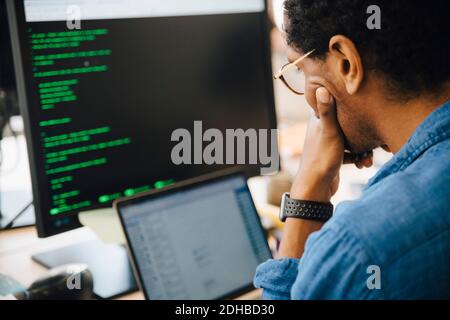 Focused male it professional using laptop while sitting in creative workplace Stock Photo