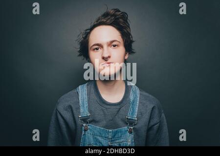 Portrait of confident young man wearing overalls on gray background Stock Photo