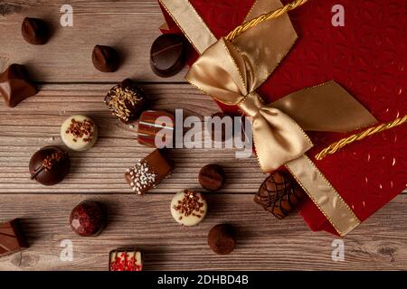 Assorted chocolates in elegant red gift pack with golden ribbon put on top of a wooden table. A stylish christmas and valentines day gift option with Stock Photo