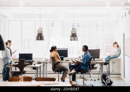 Male and female computer engineers working against window in creative office Stock Photo