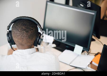 High angle view of male programmer coding over computer on desk while sitting in office Stock Photo