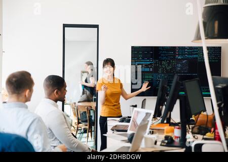 Female hacker interacting with colleagues while giving presentation in office Stock Photo