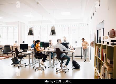 Female computer hacker giving presentation to programmers during meeting in creative office Stock Photo