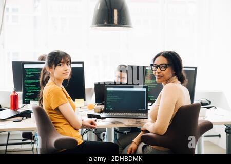 Portrait of female computer hackers sitting desk in creative office Stock Photo