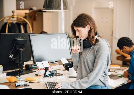 Female computer programmer analyzing data on laptop at desk in office Stock Photo