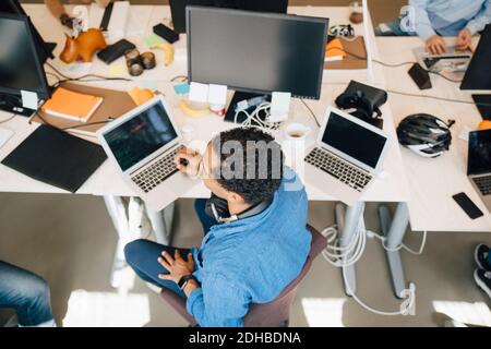 High angle view of computer hacker with laptop sitting at desk in office Stock Photo