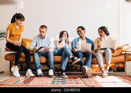 Happy colleagues working together while sitting on sofa in creative office Stock Photo