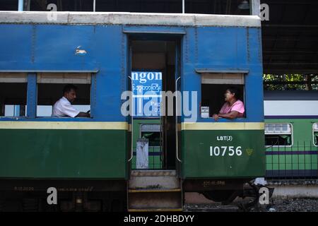Yangon, Myanmar - December 31, 2019: Two local burmese people sitting on the traditional circular train at the railway station Stock Photo