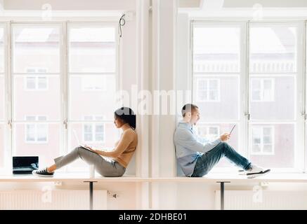 Full length side view of computer programmers working over technologies at desk by window in creative office Stock Photo