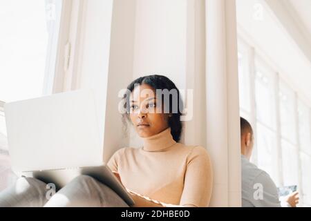 IT programmer using technologies by window in office Stock Photo
