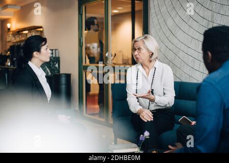 Senior businesswoman sharing ideas with colleagues while sitting on couch Stock Photo