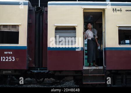 Yangon, Myanmar - December 31, 2019: A local burmese man standing in the door opening in ordinary class of the traditional circular train at the railw Stock Photo