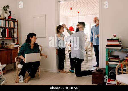 Happy family looking at man measuring daughter's height against wall at doorway Stock Photo