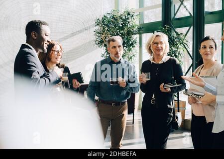 Colleagues listening to businesswoman while having coffee in meeting at office Stock Photo