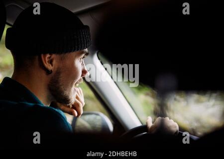 Smiling young man wearing knit hat while driving car Stock Photo