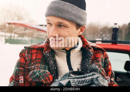 Close-up of thoughtful smiling man having coffee against car Stock Photo