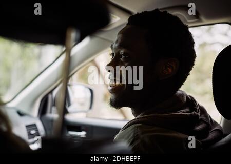 Smiling young man looking away while sitting in car Stock Photo