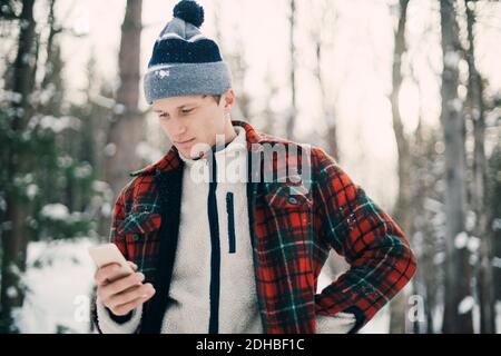 Man using smart phone while standing at park during winter Stock Photo