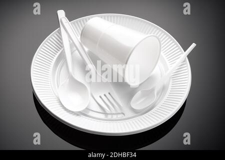 Plastic dishware. White cup, plate, fork and spoon Disposable plastic waste Stock Photo