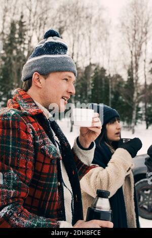 Smiling man standing with friend and having coffee during winter Stock Photo