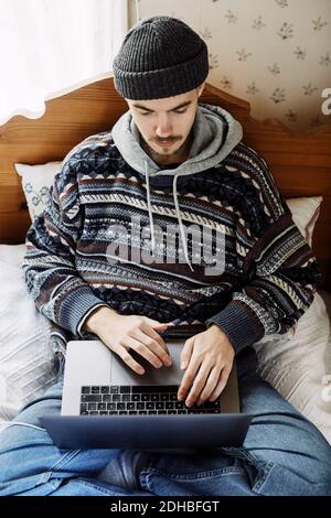 High angle view of young man using laptop while relaxing on bed at home Stock Photo