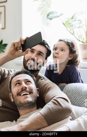 Fathers and playful daughter taking selfie through smart phone at home Stock Photo