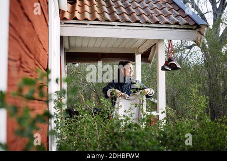Smiling young woman drying clothes while standing outside cottage Stock Photo