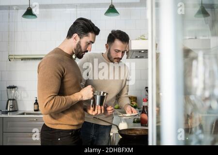 Gay couple preparing food in kitchen at home Stock Photo