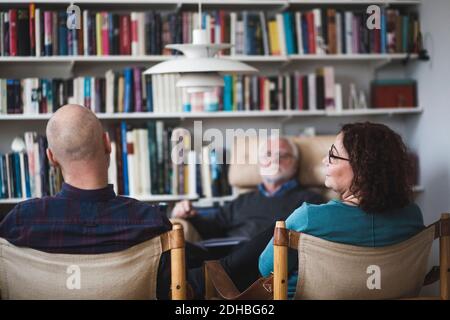 Mature couple talking while sitting with therapist at home office Stock Photo