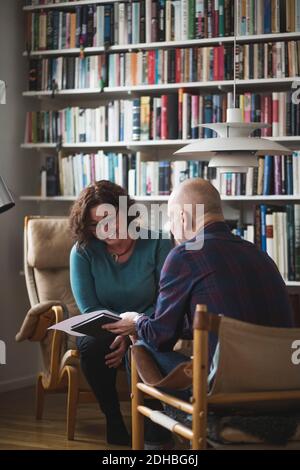 Male therapist showing document to smiling patient at home office Stock Photo