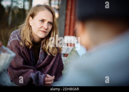 Serious young woman with blond hair looking away while sitting outside during sunset Stock Photo
