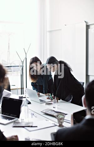 Businesswomen working over laptop at conference table in board room Stock Photo