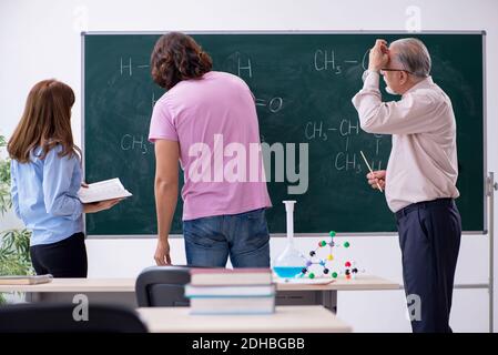 Old chemist teacher and two students in the classroom Stock Photo