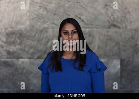 Portrait of confident businesswoman with black hair standing against wall in office Stock Photo
