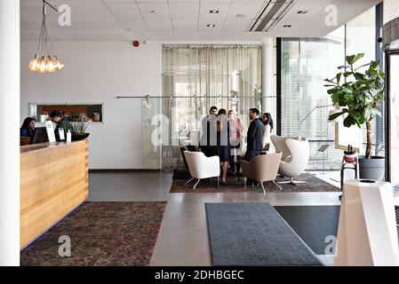 Business people talking while standing in lobby at office Stock Photo