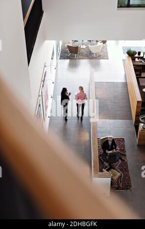 Full length of female colleagues discussing walking  in corridor Stock Photo