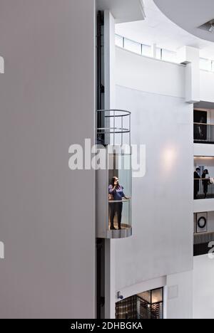 Businesswoman in elevator with colleagues discussing at balcony Stock Photo