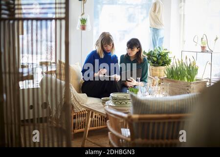 Female partners looking at notepad while discussing at boutique Stock Photo