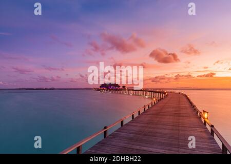Sunset on Maldives island, luxury water villas bungalows resort wooden pier. Beautiful sky clouds and sunrise beach background summer vacation holiday Stock Photo