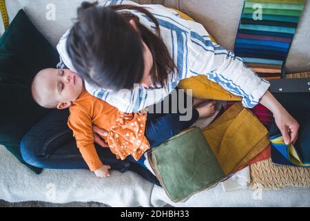 High angle view of design professional working while sitting with sleeping daughter on sofa at home office Stock Photo