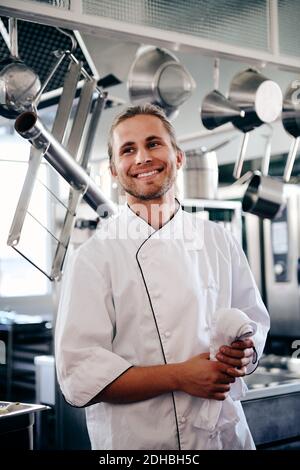 Smiling young chef holding napkin in commercial kitchen Stock Photo