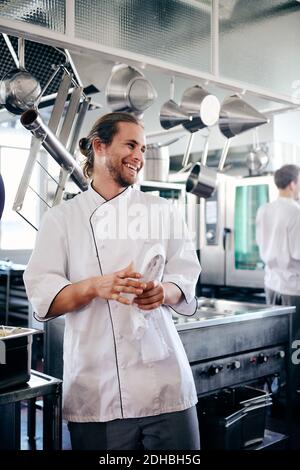 Smiling male chef holding napkin in commercial kitchen Stock Photo
