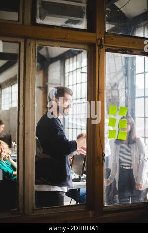 Young computer hackers having meeting in board room seen through glass at creative workplace Stock Photo