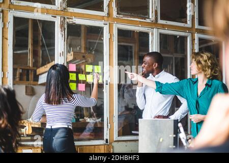 Confident computer programmers using adhesive notes to pen down their innovative ideas during meeting at workplace Stock Photo